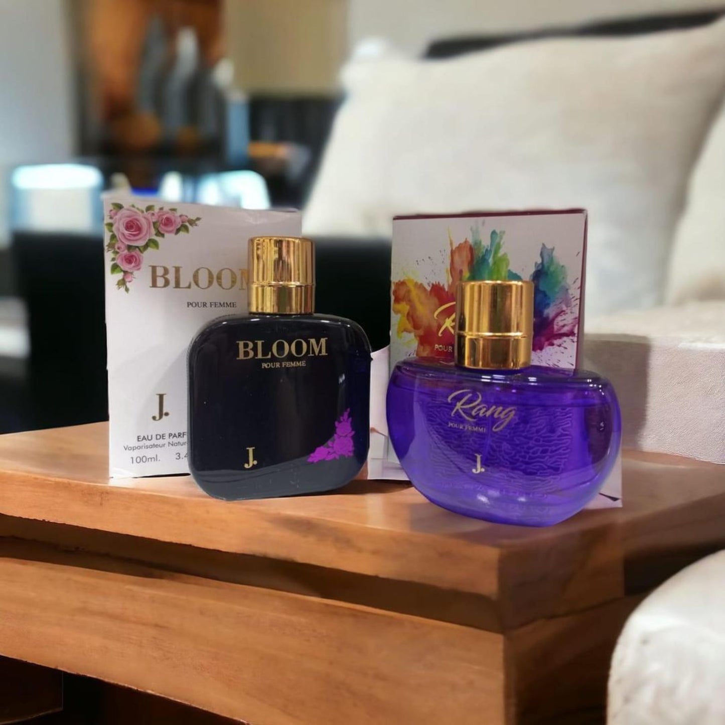 Two perfume bottles, one black and one purple, on a wooden surface with their packaging.
