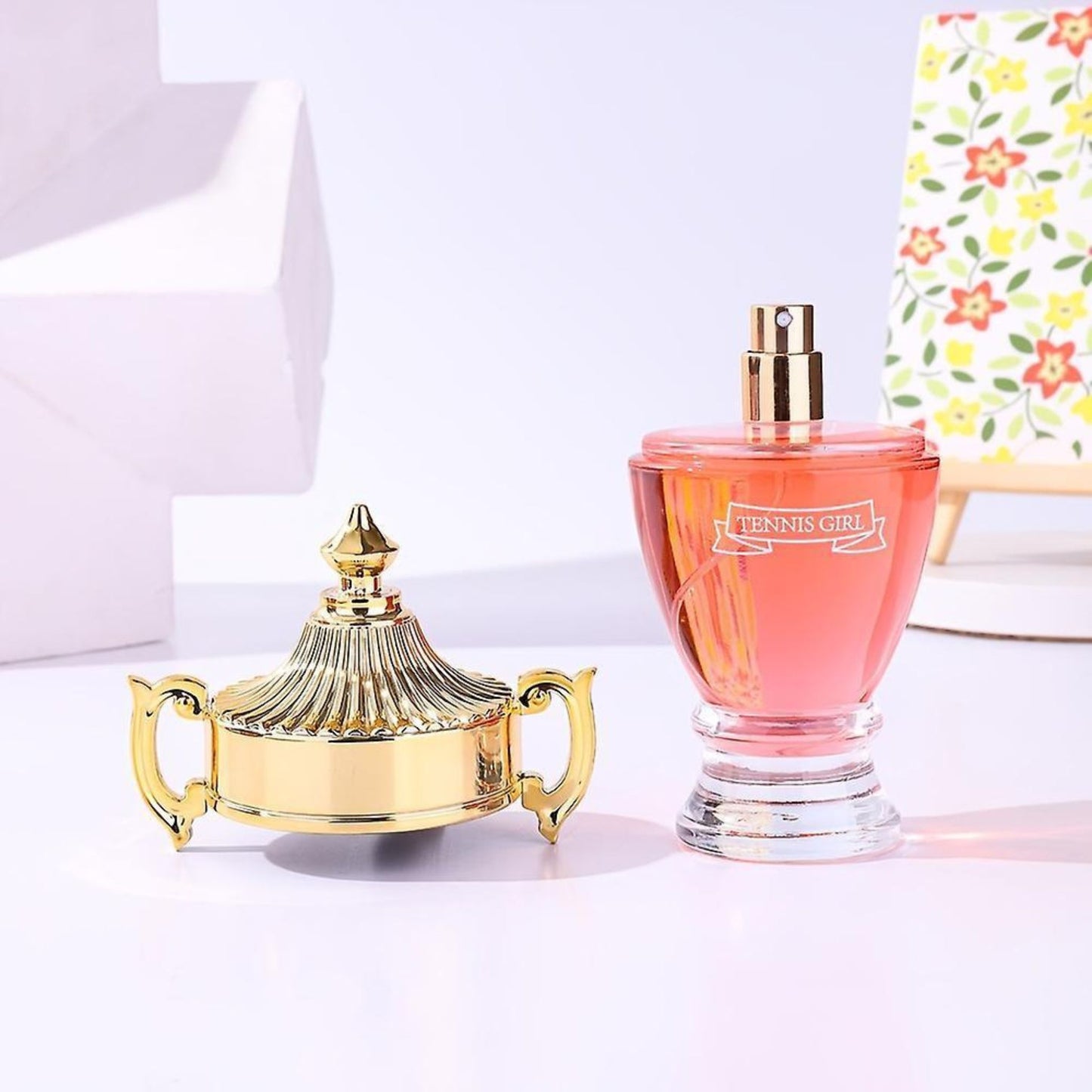 Gold decorative item and pink perfume bottle on a light background