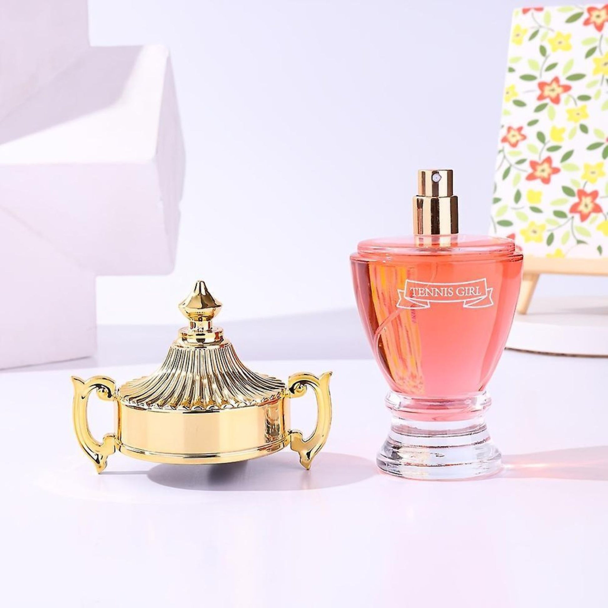 Gold decorative item and pink perfume bottle on a light background