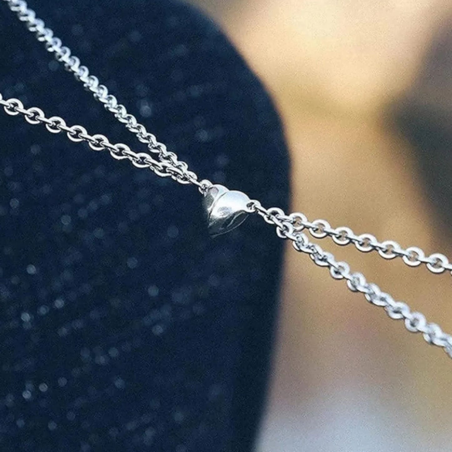 Close-up of a silver chain necklace on a textured blue background